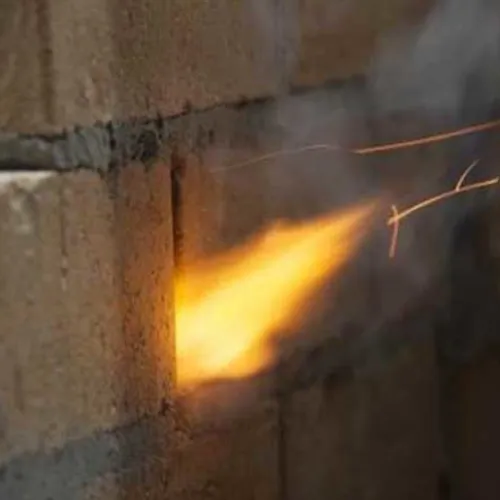 Several sparks and a flame erupting from a masonry weep hole.